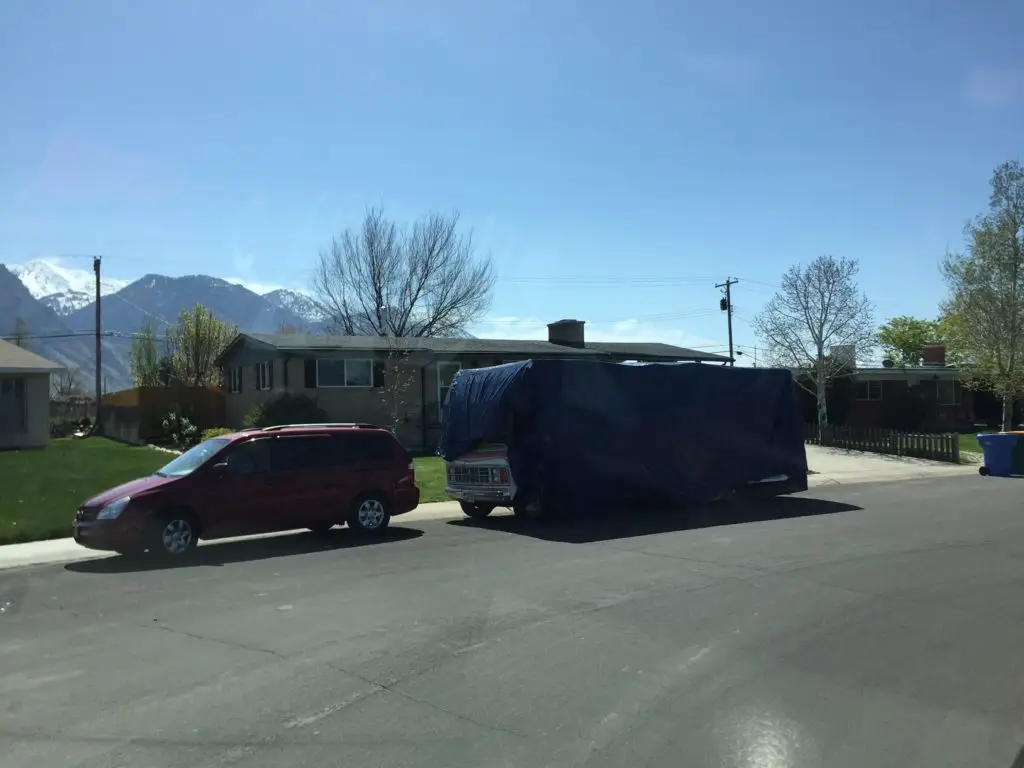 RV/Motorhome on the road, blocking street sweeper's way.
