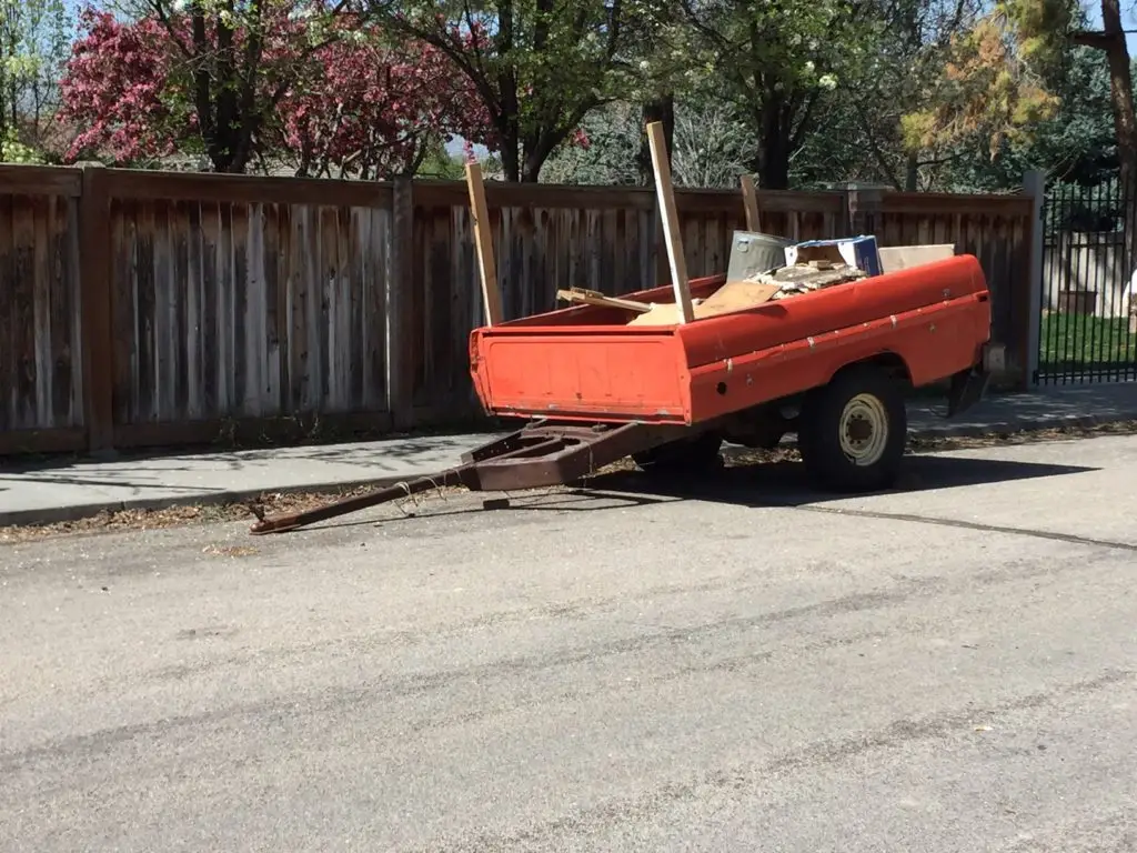 Trailer on the road blocking street sweeper's way.