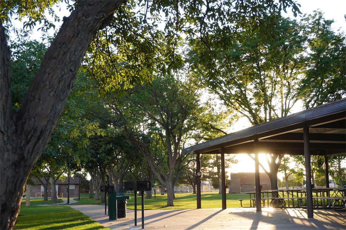 The sunset shines through a pavilion in the park.